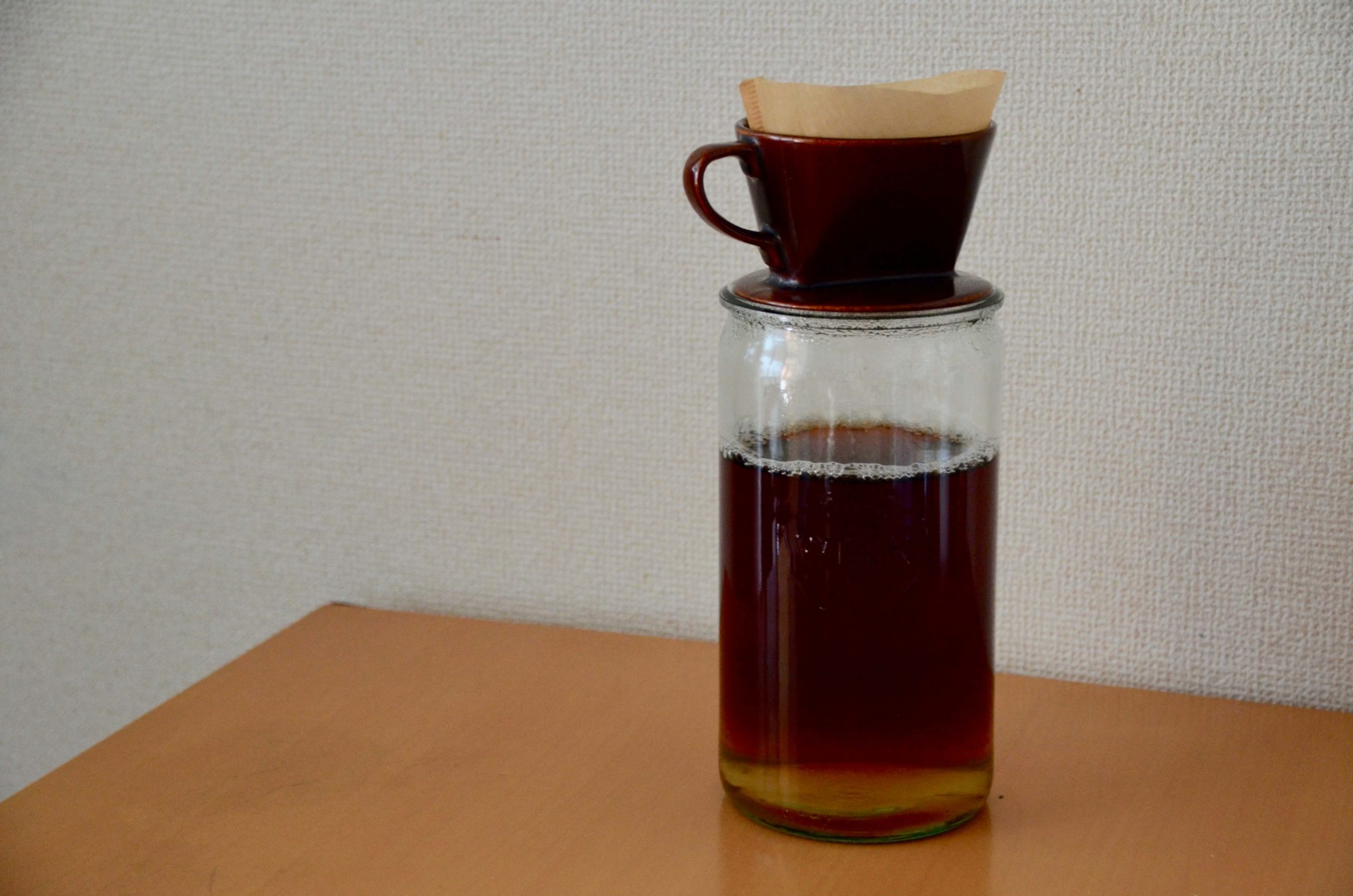 コンブチャ作成過程　1.5リットル入りの耐熱容器瓶の上にコーヒードリッパーが置かれ、紅茶を濾している